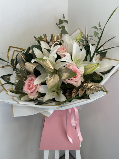 Miss bling queen - Handtied of pink roses and white lillies in a box with lush green foliage with some gold sprayed leaves.